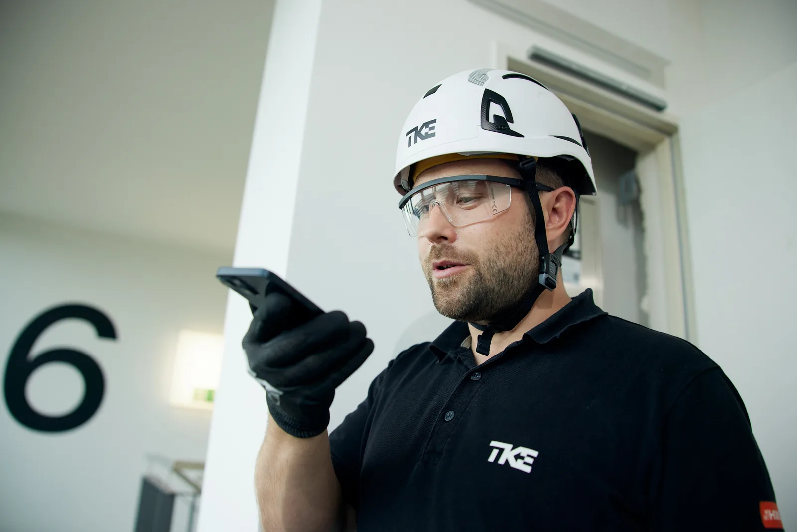 A TKE elevator technician talking to phone, presumably to an AI agent