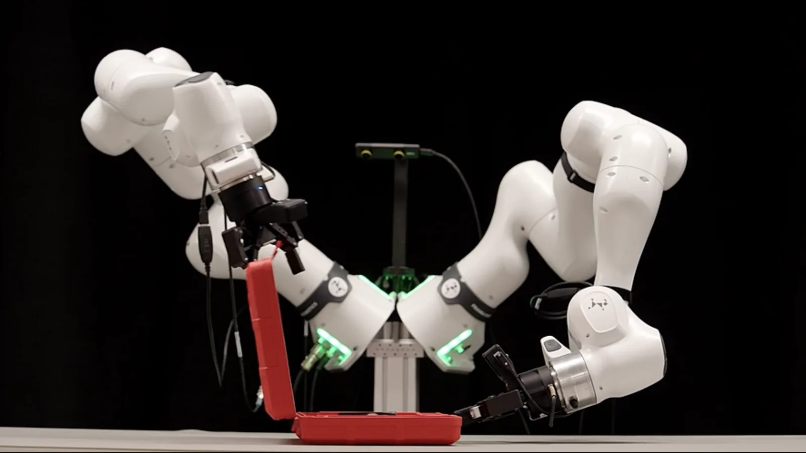 A photograph of two robot arms closing a box